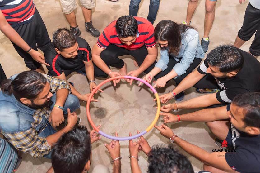 Corporate team doing hula hoop pass challenge during team building session