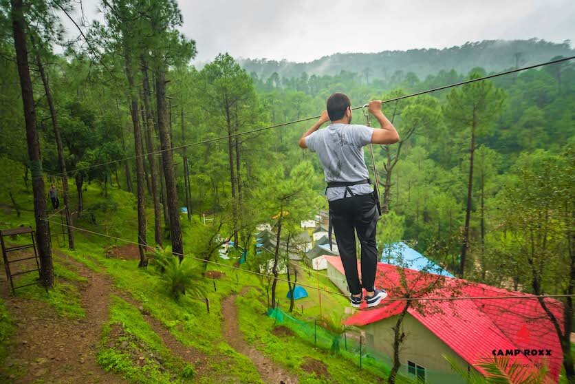 Person on zipline soaring over pine forest canopy at Camp Roxx corporate offsite